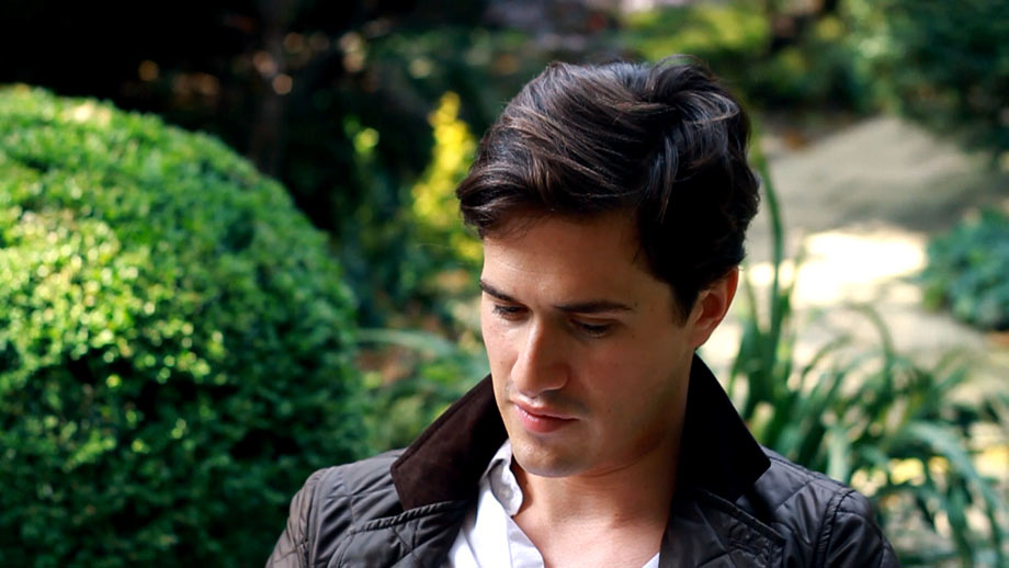 Portrait of Charlie Siem wearing a Barber jacket; Siem looks away from the camera down onto his lap.