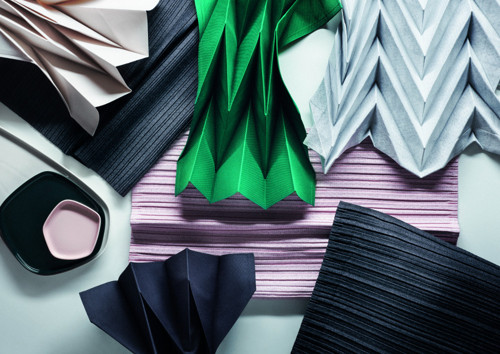 Napkin in Light Grey, Emerald, Ivory, and Dark Grey, Placemat in Pink, Table Runner in Dark Grey, Plate in Dark Green, Cup in Pink © Iittala X Miyake